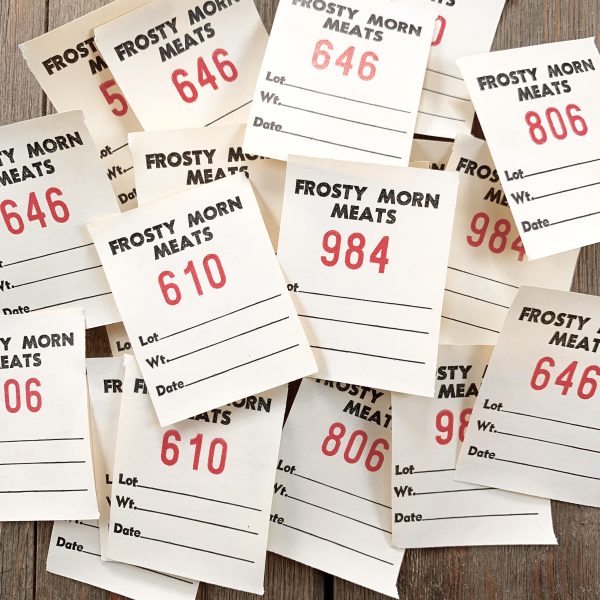 A pile of cream-colored vintage Frosty Morn Meats tickets with various red numbers on each