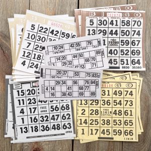 Twenty assorted paper bingo and lotto cards in cream, brown, beige, black, and white