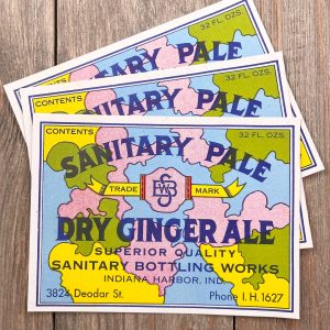 3 Colorful vintage soda labels that say “Sanitary Pale Dry Ginger Ale” and feature an abstract map in the background.