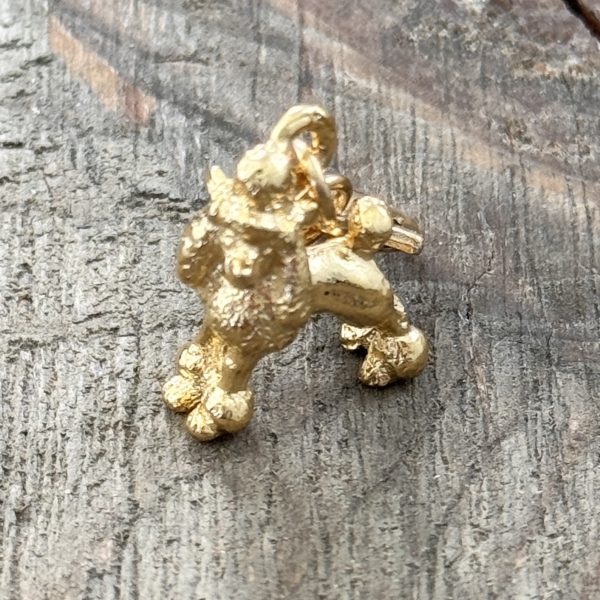 1 Handmade vintage gold-tone poodle charm with lobster clasp on a wood background.