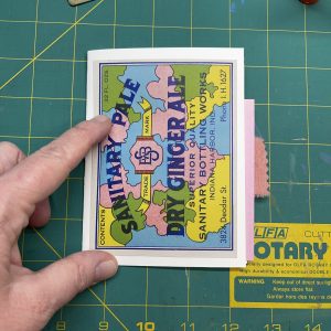 A mini handmade junk journal with a colorful vintage soda label on the cover