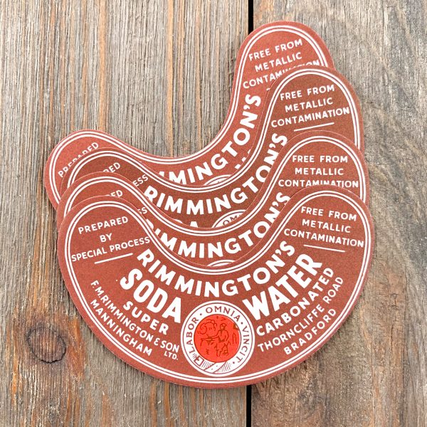 A pile of 4 vintage crescent-shape brown, red and white British Soda Water neck labels