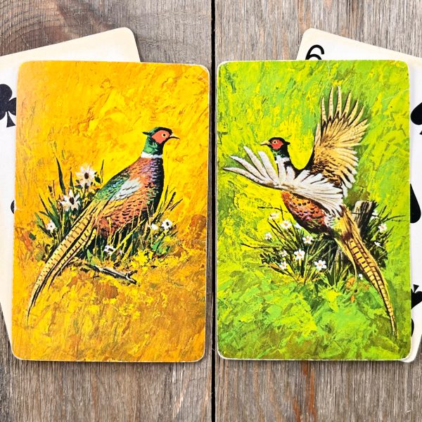 4 Assorted vintage playing cards in 2 piles - one is a standing pheasant on a yellow background and the other is a flying pheasant on a green background