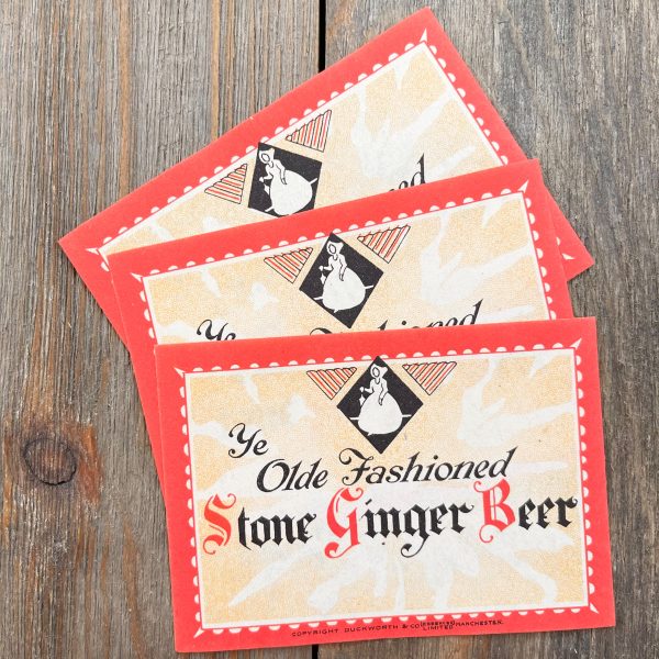 3 Vintage red and cream colored soda labels with a milk maid icon and text that reads Ye Olde Fashioned Stone Ginger Beer