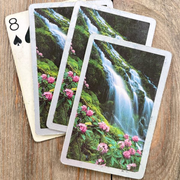 Four vintage playing cards featuring a waterfall next to a flowery grassy hill