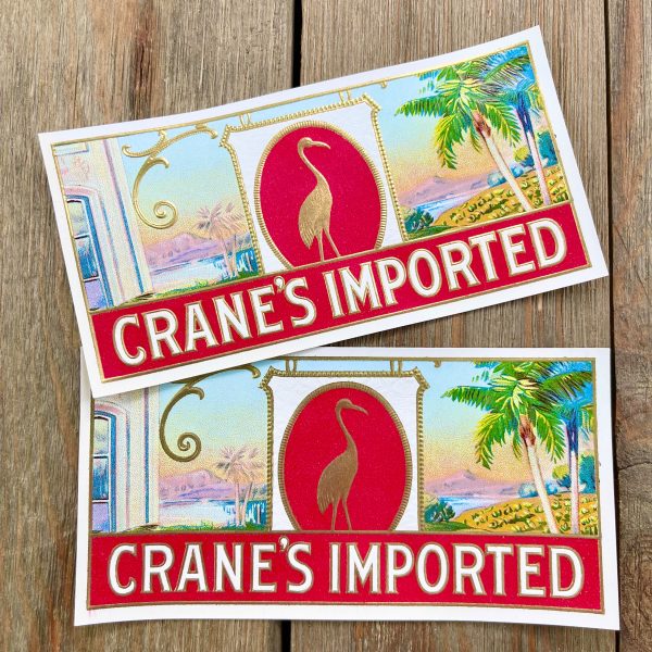 Two vintage Crane’s Imported cigar box labels featuring a beach scene and gold crane