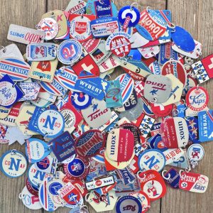 A pile of red white and blue handmade junk journal charms made from vintage metal Dutch advertising stick pins
