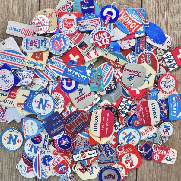 A pile of red white and blue handmade junk journal charms made from vintage metal Dutch advertising stick pins